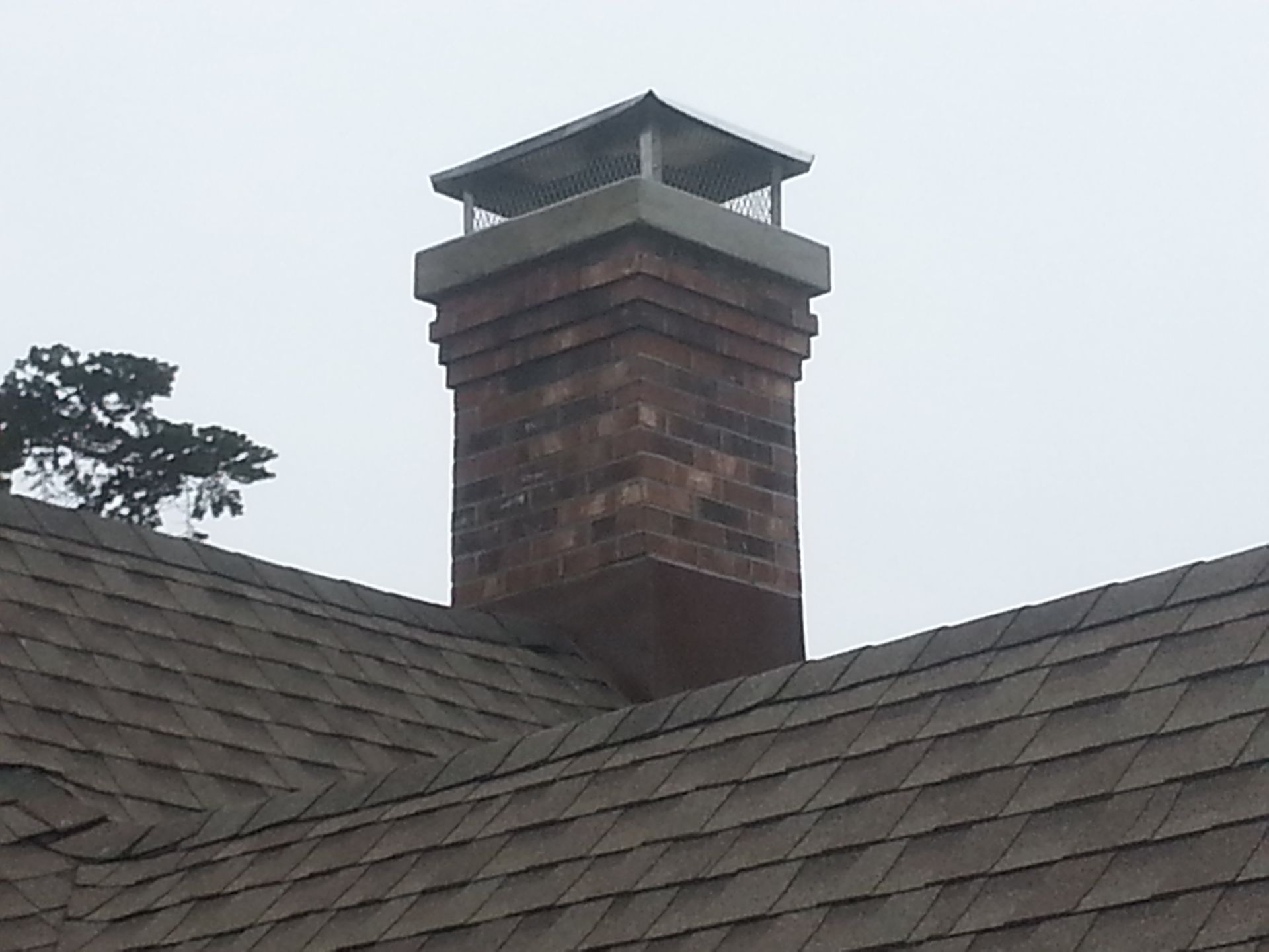 a chimney on top of a roof with a tree in the background