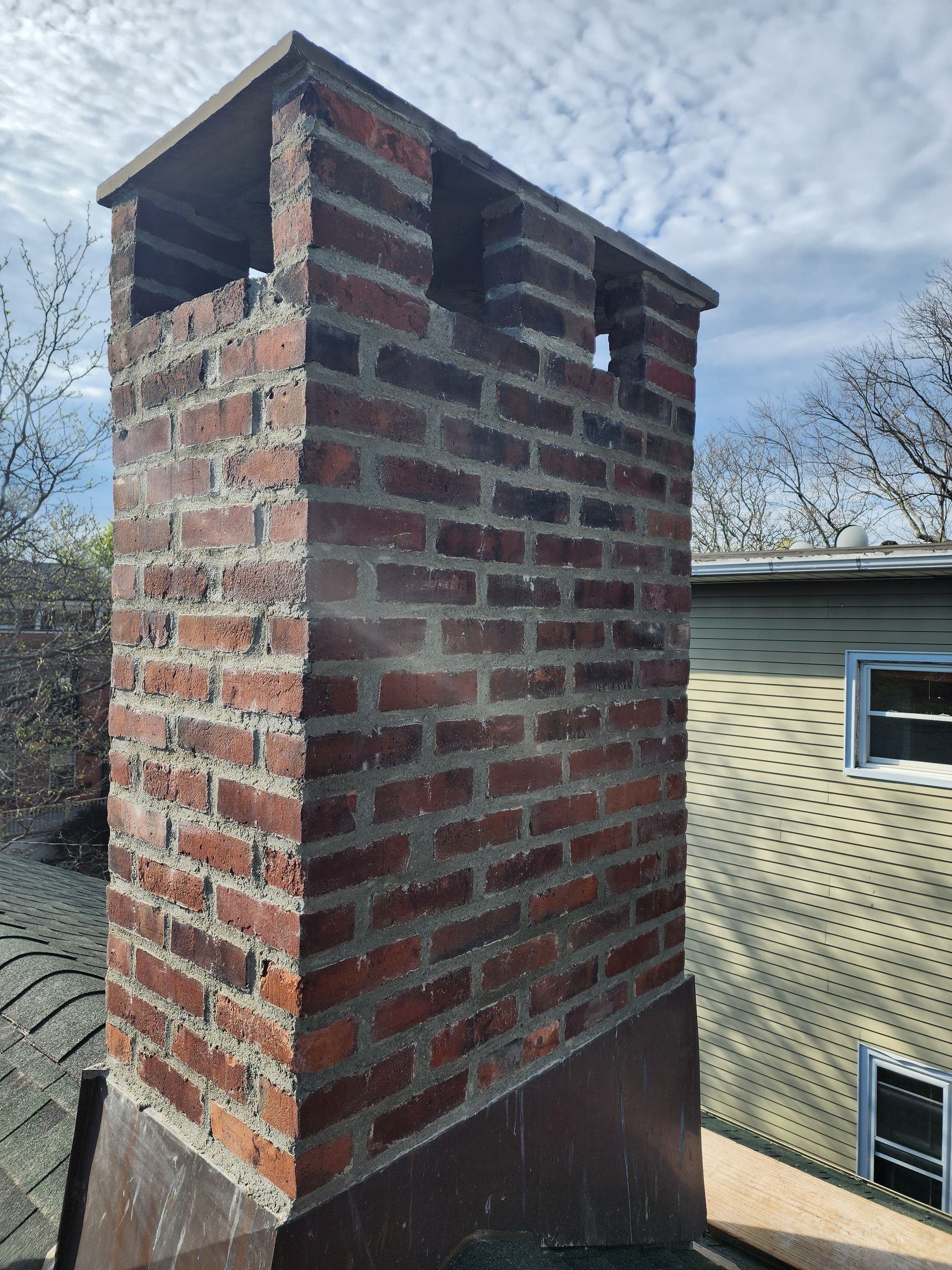 a brick chimney is sitting on top of a roof next to a house