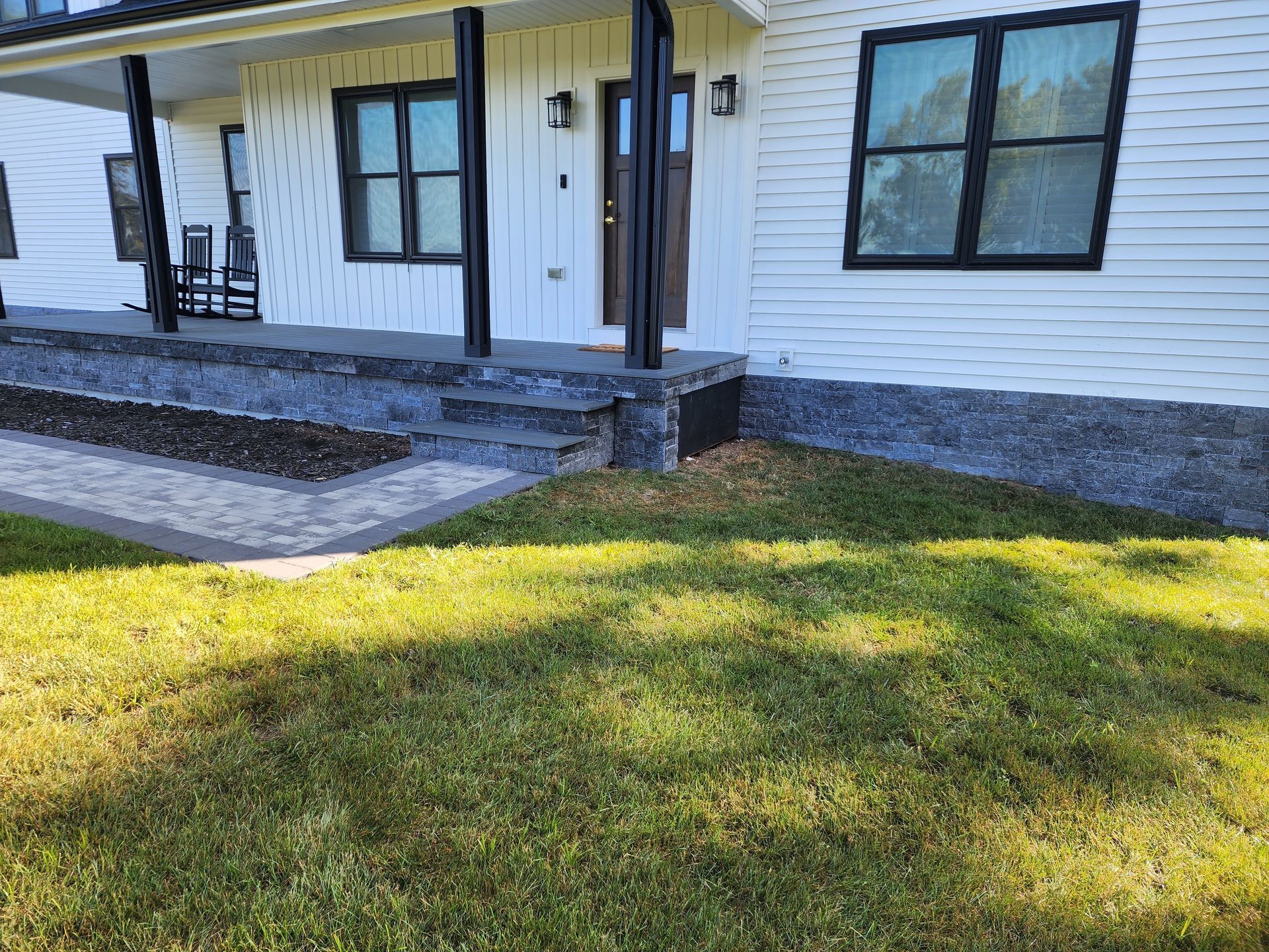 a white house with a porch and a lush green lawn in front of it