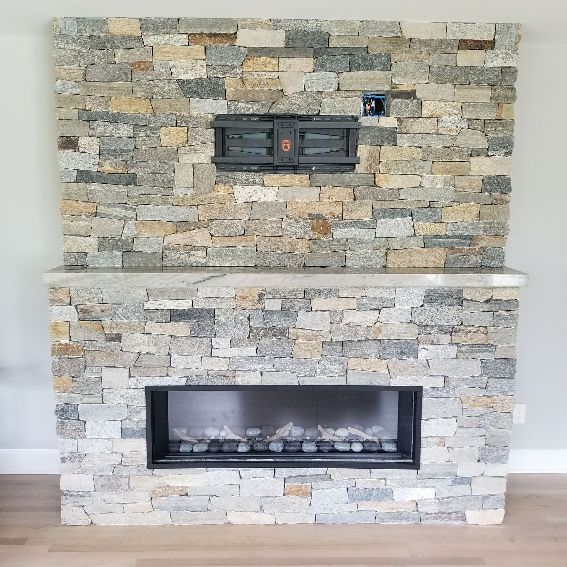 a fireplace with a stone wall and a flat-screen tv mounted on it
