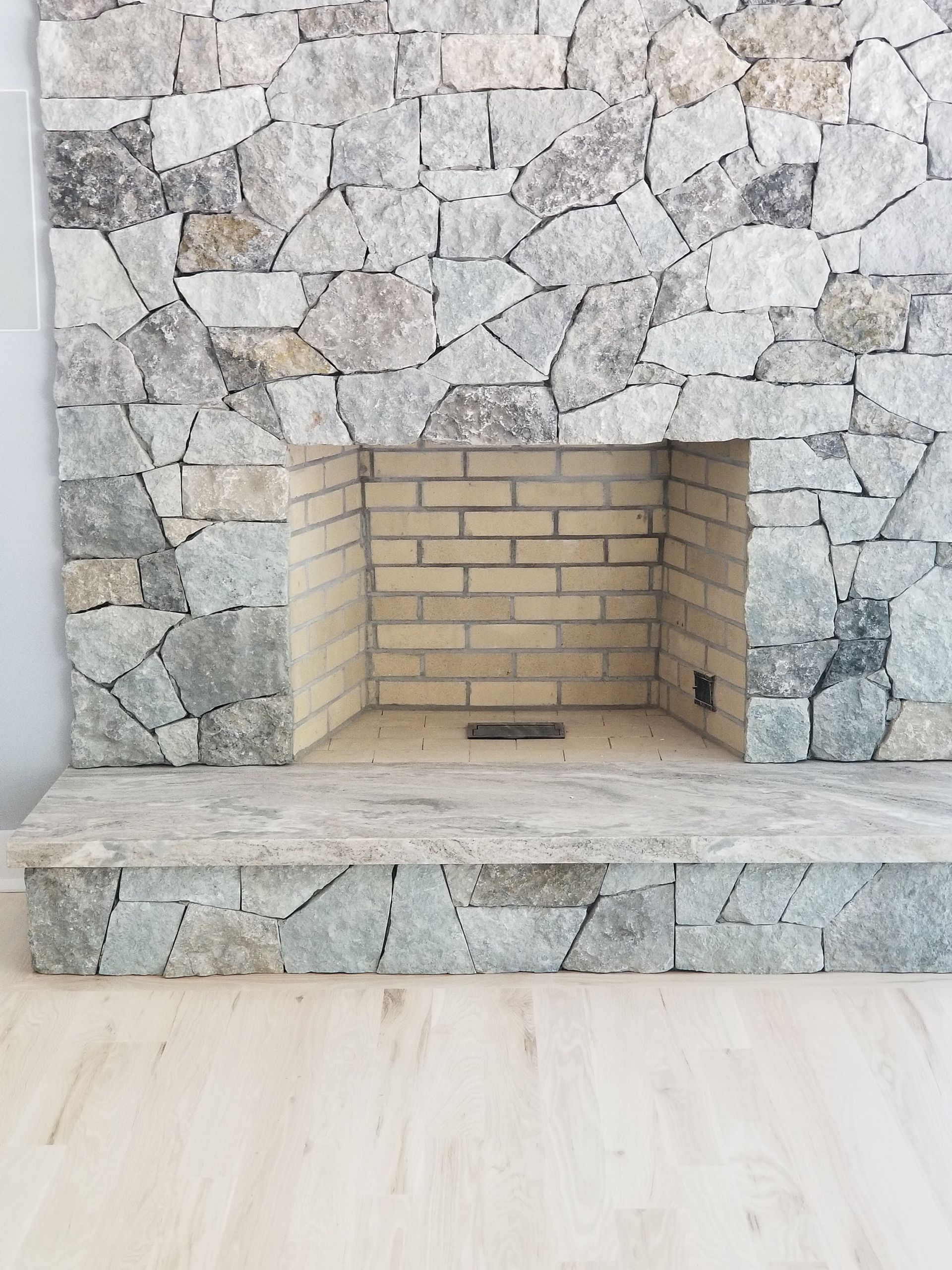 a brick fireplace with a stone wall surrounding it in a living room