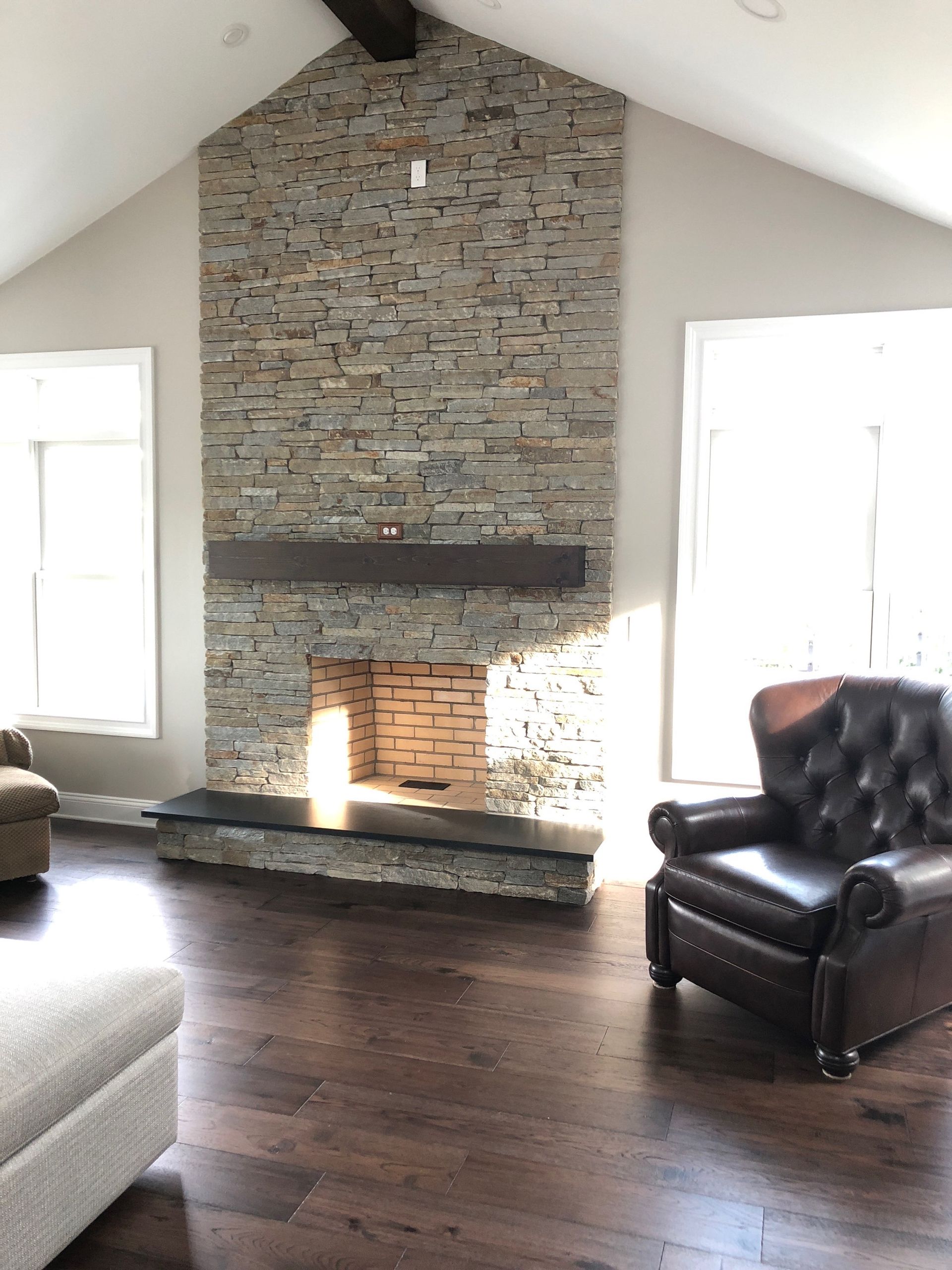 a living room with a stone fireplace and a leather chair