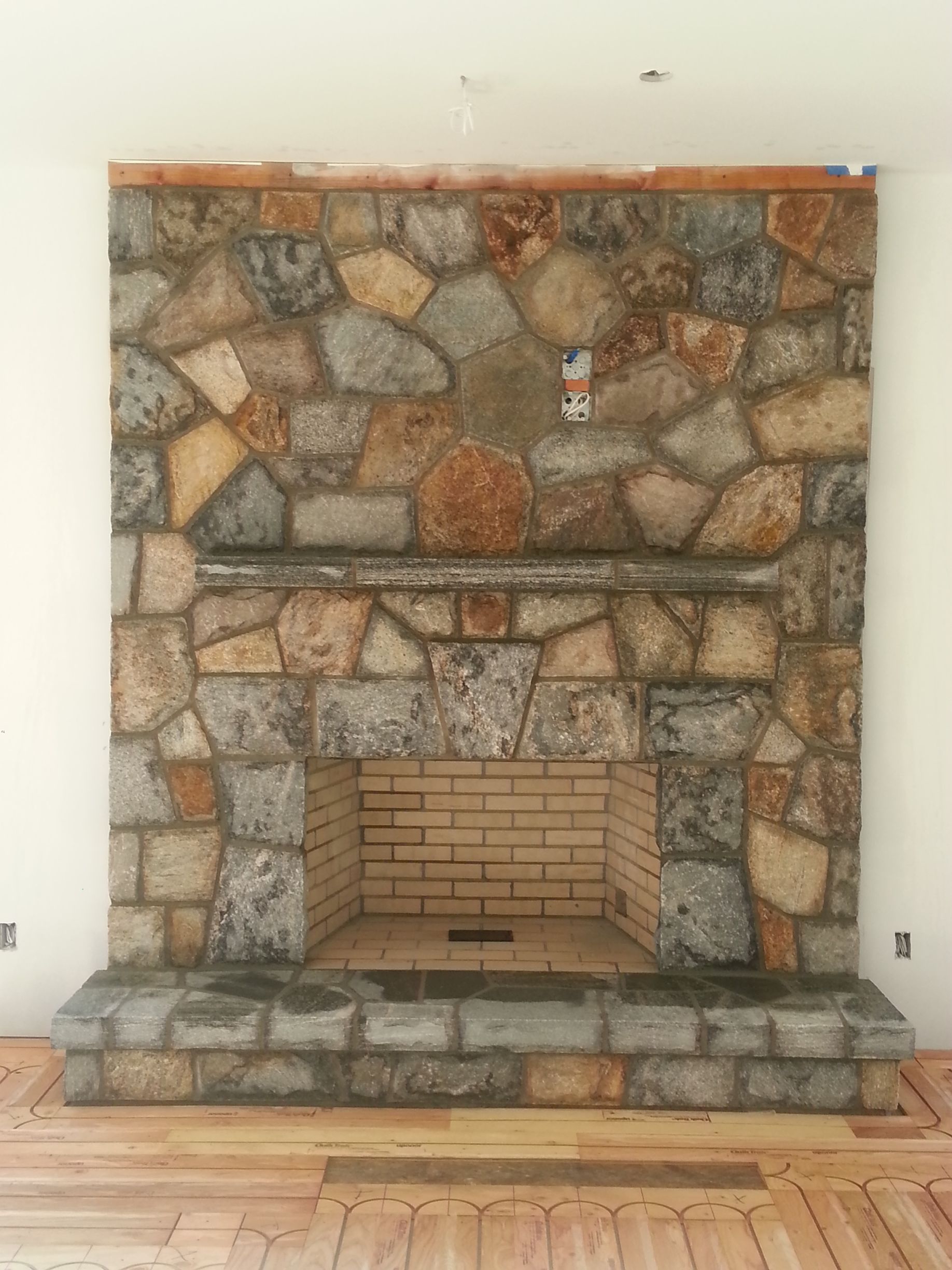 a stone fireplace in a living room with a wooden floor