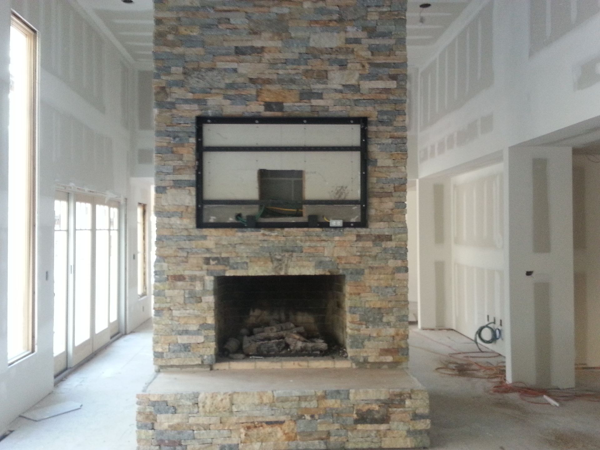 a stone fireplace with a flat-screen tv above it