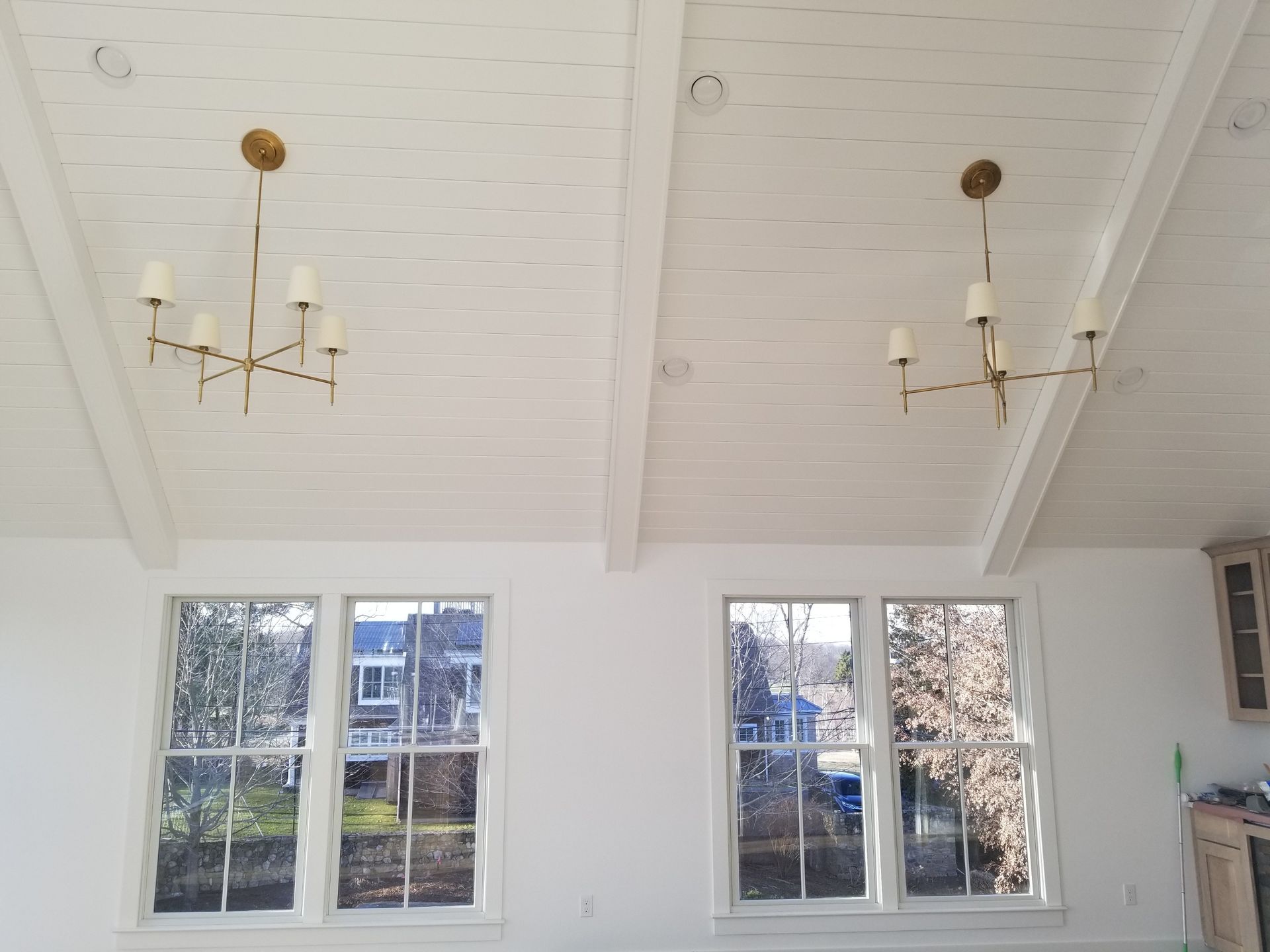 two chandeliers are hanging from the ceiling of a room with windows