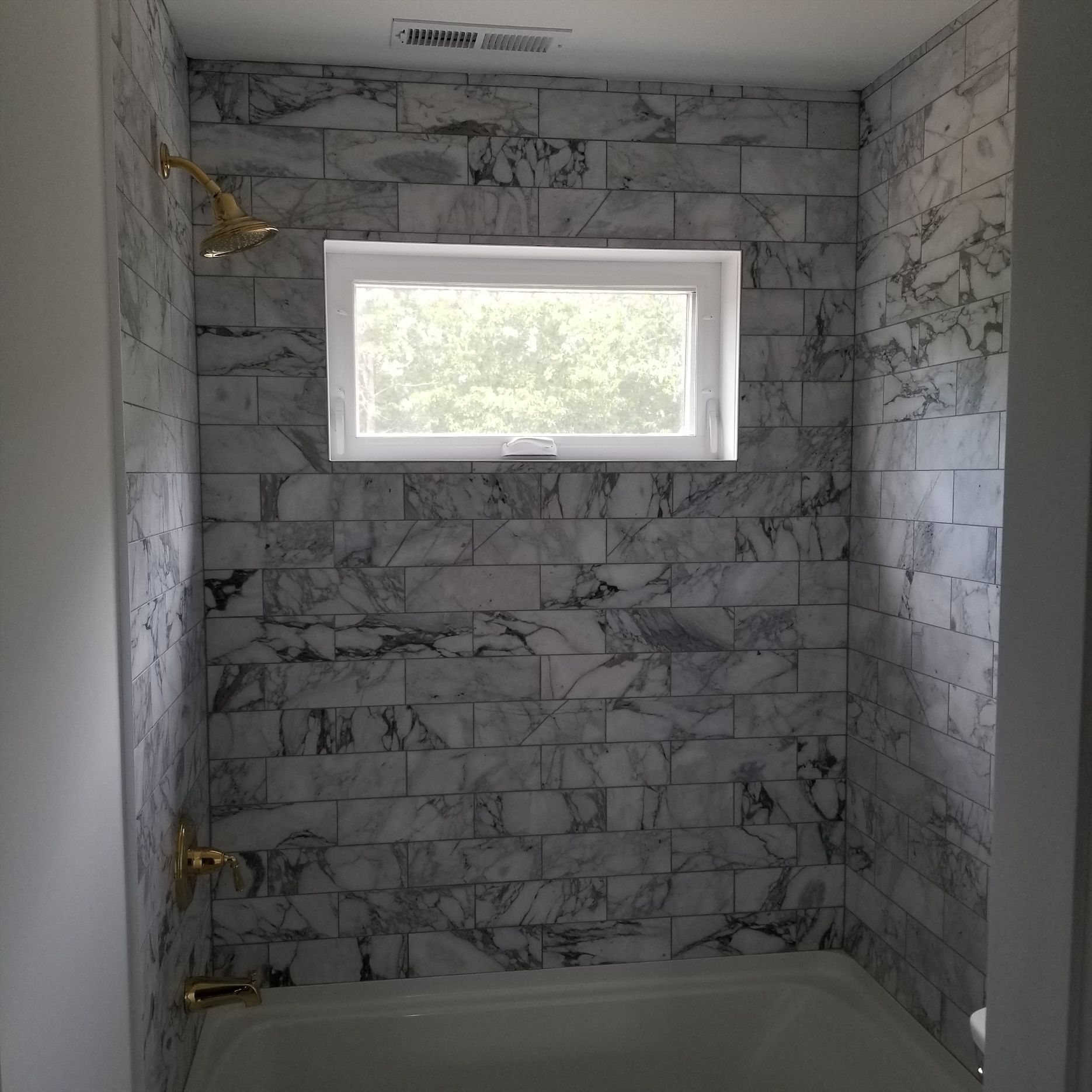 a bathroom with marble tile walls and a window