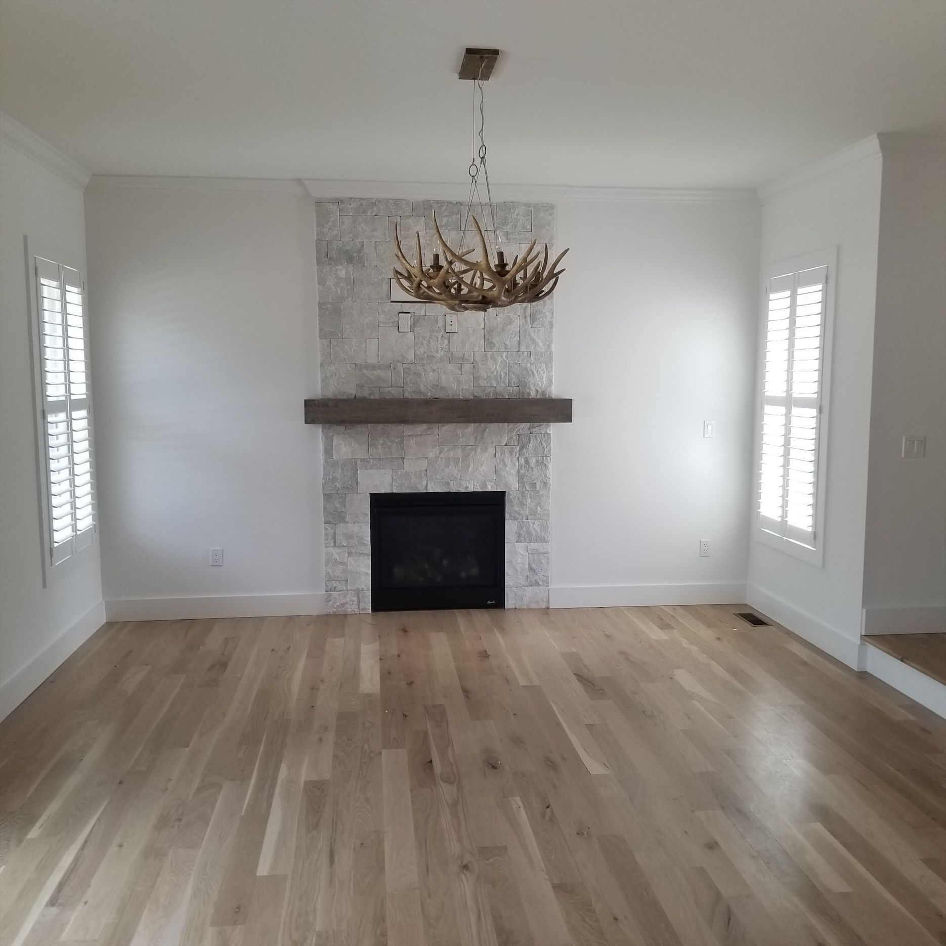 an empty living room with a fireplace and a chandelier