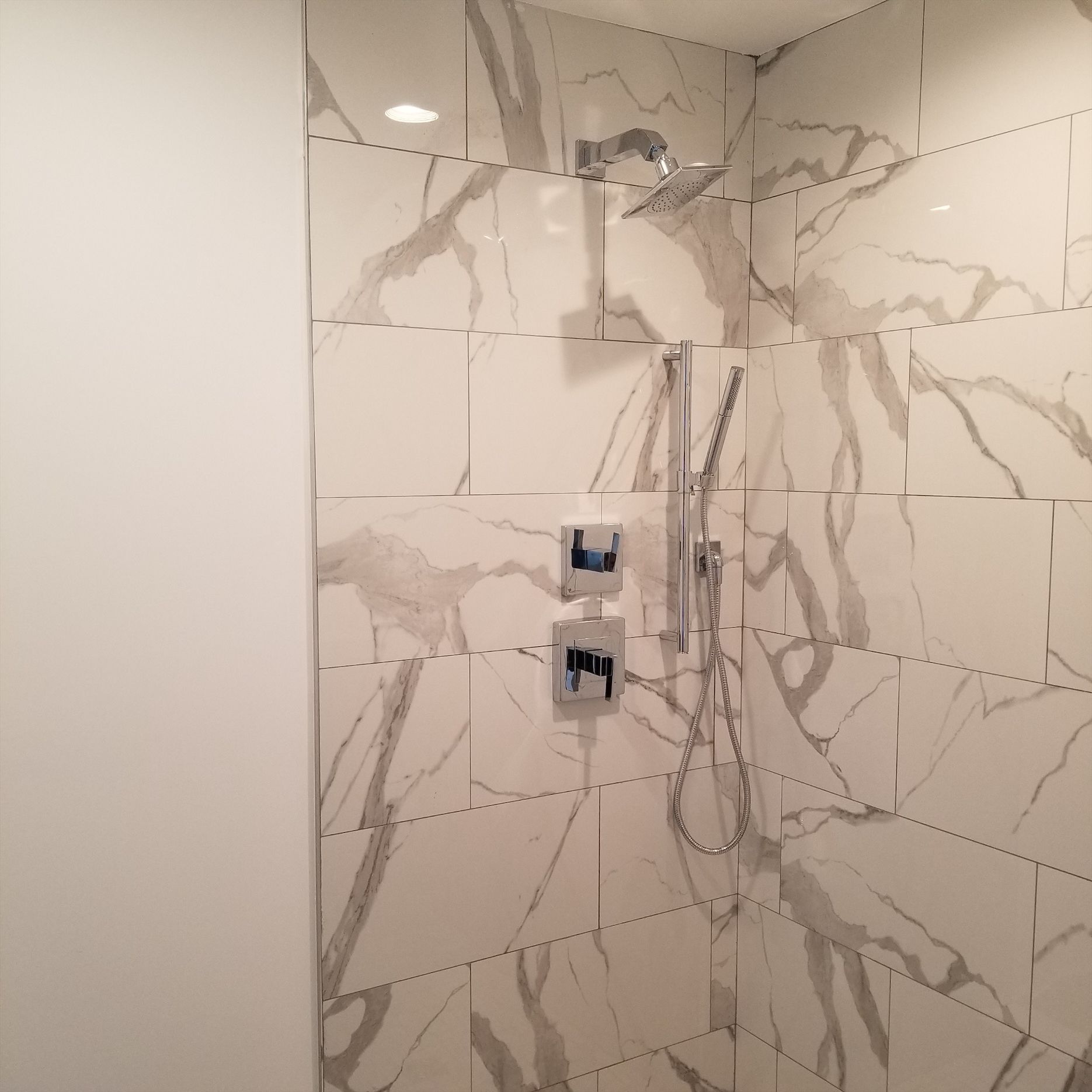 a bathroom with marble tiles and a shower head