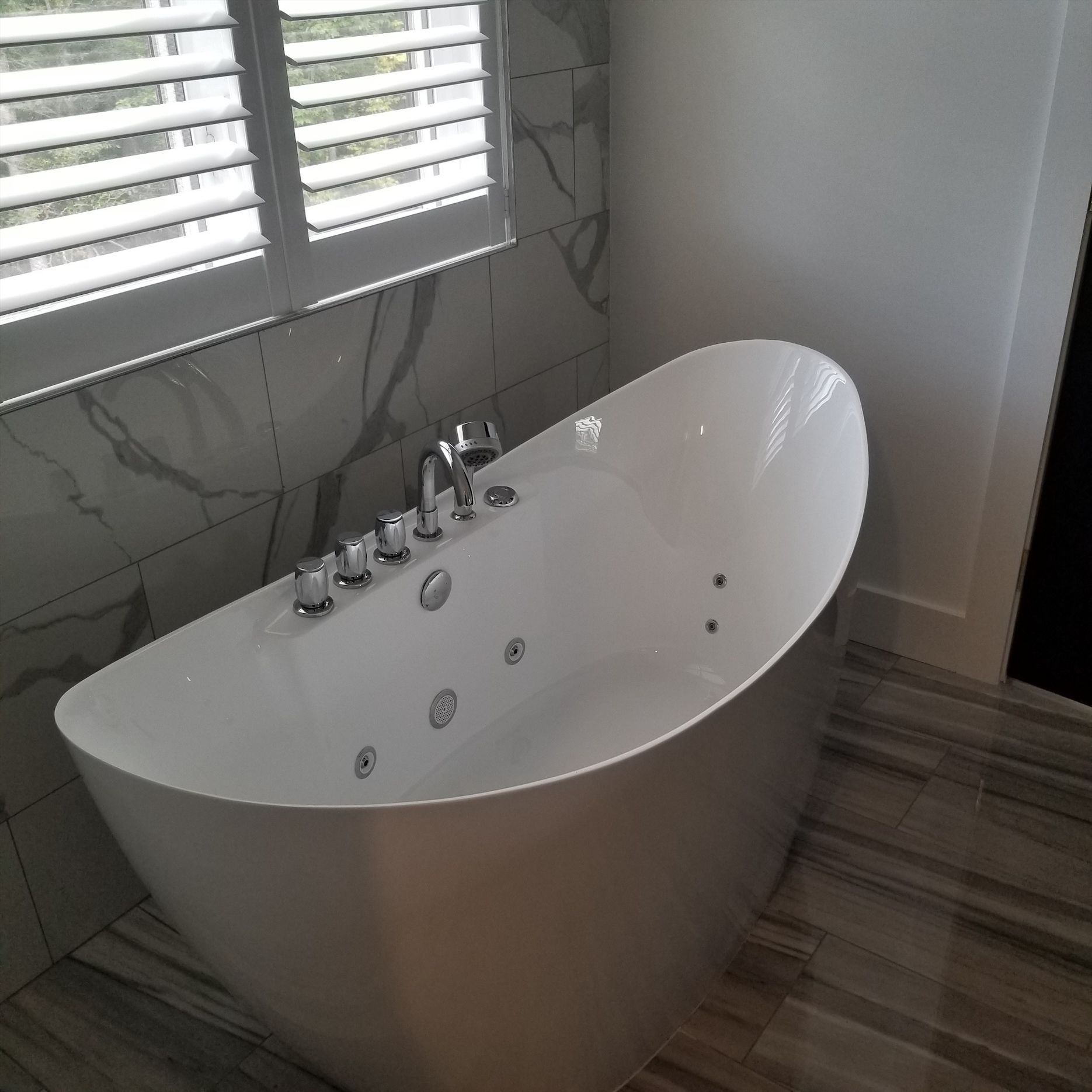 a white bathtub is sitting in a bathroom next to a window