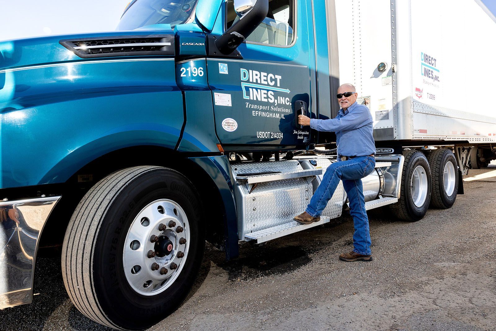 Man steps onto a teal semi-truck with a white trailer