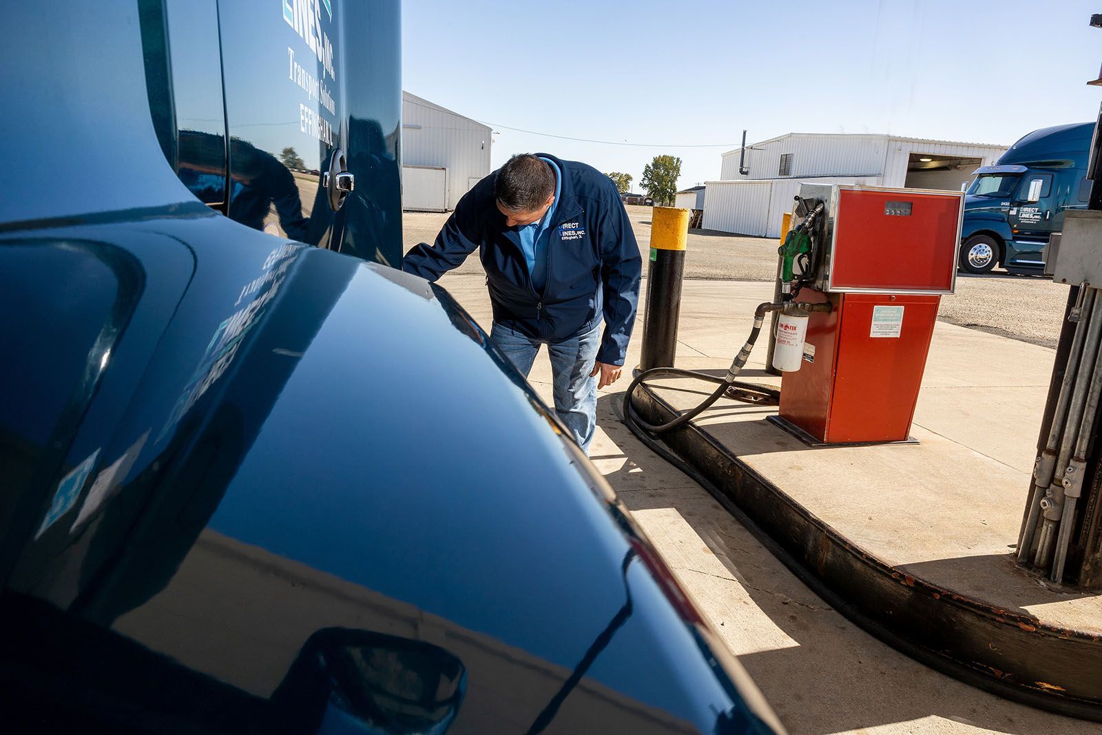 A man fueling a semi-truck at a gas pump