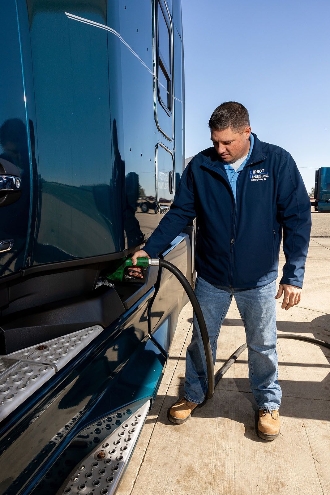 A person fueling a semi-truck at a truck stop