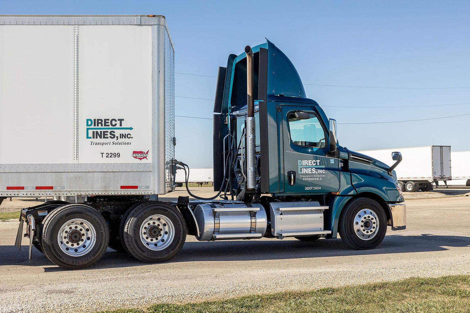Semi-truck with a white trailer, parked on a gravel road