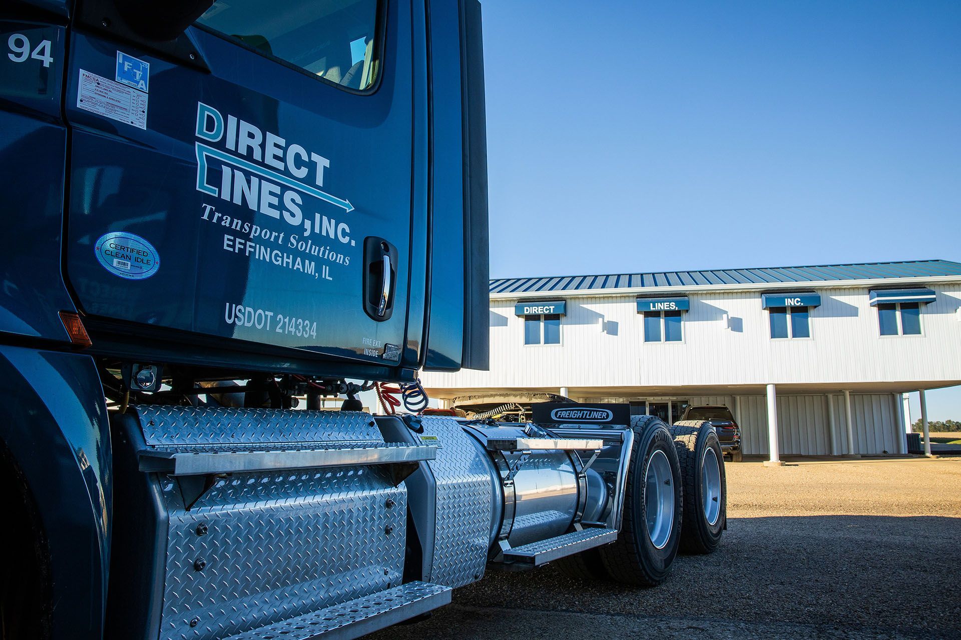 Dark blue semi-truck parked outside a white building