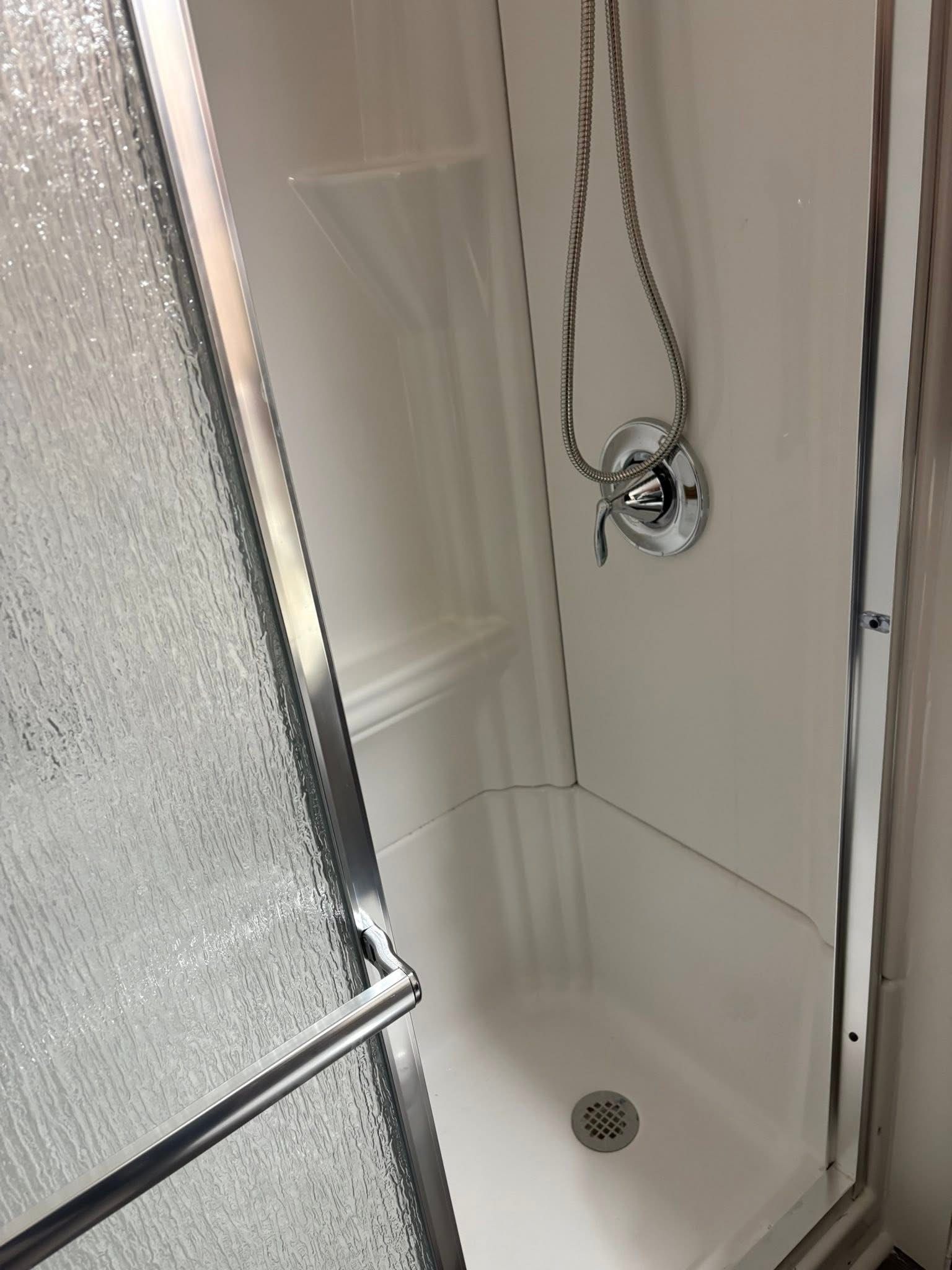 White shower stall with textured glass door and silver fixtures.