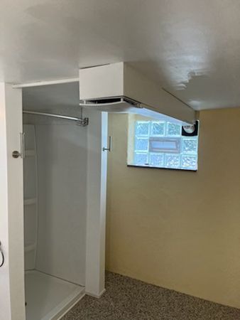 White bathroom with shower stall, window with glass blocks, and light yellow walls.
