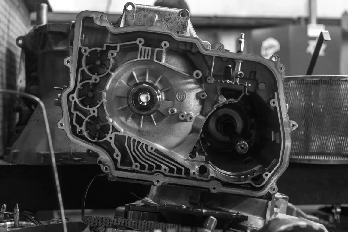 Car engine transmission housing with exposed gears on a workbench in a workshop