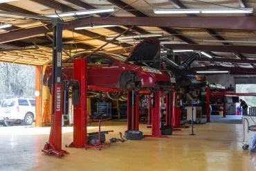 Auto repair shop with a red car lifted on a hoist and tools on the floor