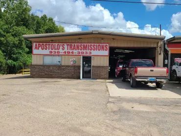 Apostolous Transmissions auto shop with cars parked outside and a truck in the driveway
