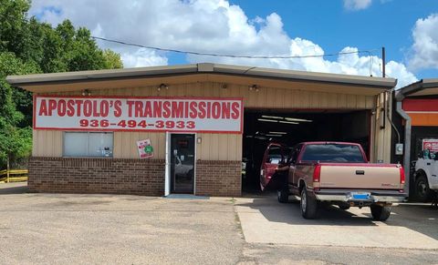 Auto repair shop with a red-and-white &ldquo;Apostolo&rsquo;s Transmissions&rdquo; sign and pickup trucks outside