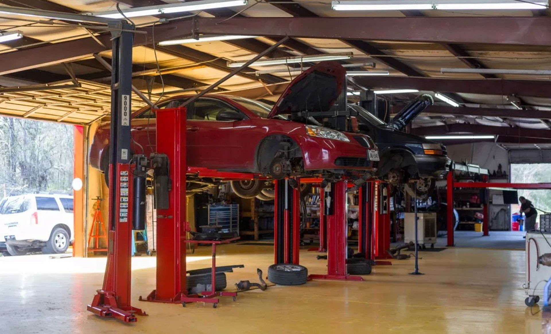 Red sports cars on lifts in a bright auto repair garage with a red hydraulic lift system