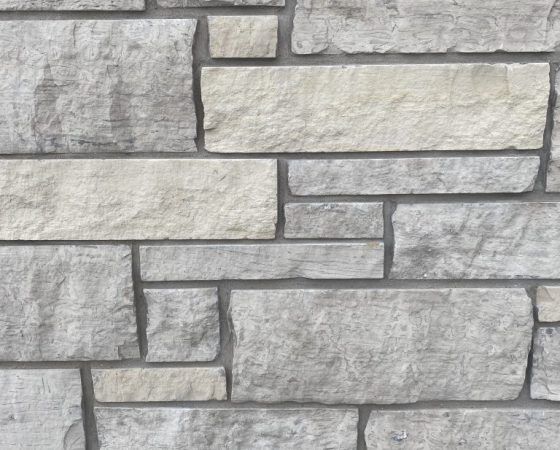 Gray stone wall with rectangular stacked blocks in varied light and dark tones