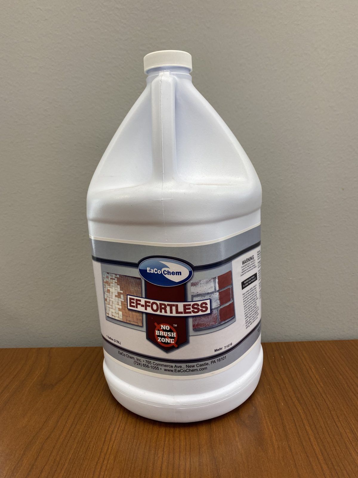White gallon jug of bleach with a gray label on a wooden table.