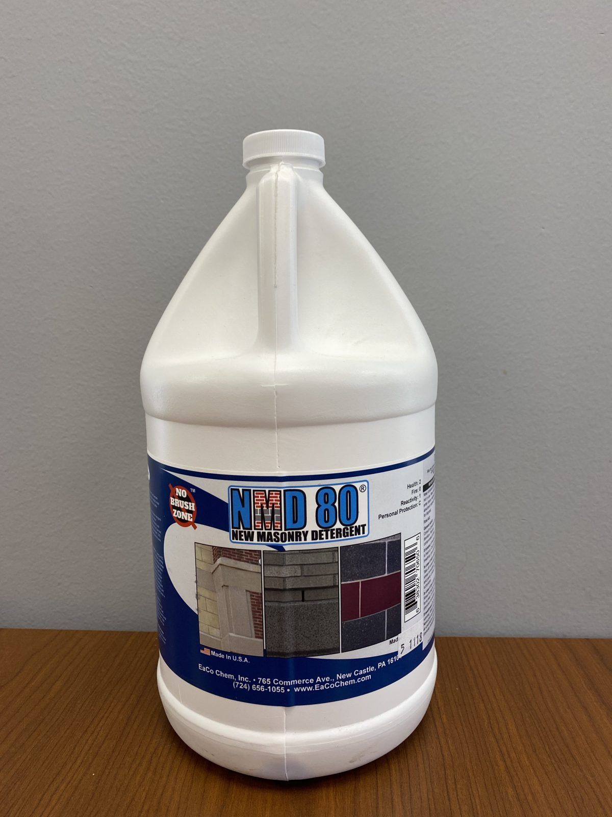 White plastic gallon jug with blue label on a wooden table against a gray wall