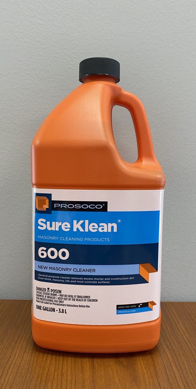 Orange jug of Sure Klean 600 cleaner with black cap and blue-white label on a table