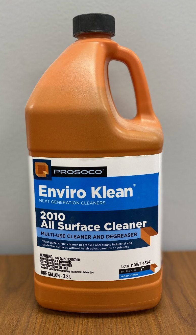 Orange jug of Enviro Kleen 2010 all surface cleaner with black cap on a wooden table