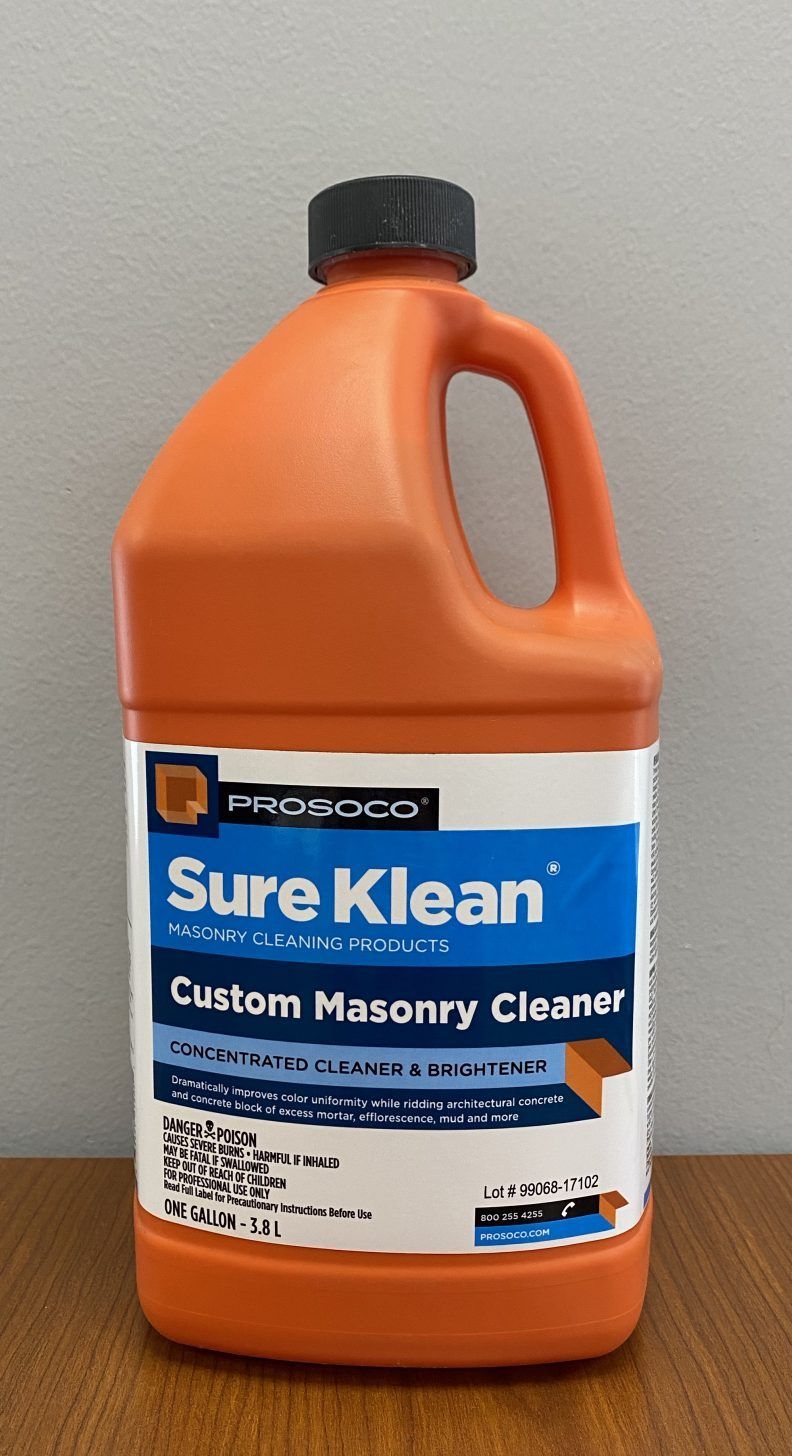 Orange jug of Sure Klean custom masonry cleaner on a wooden surface