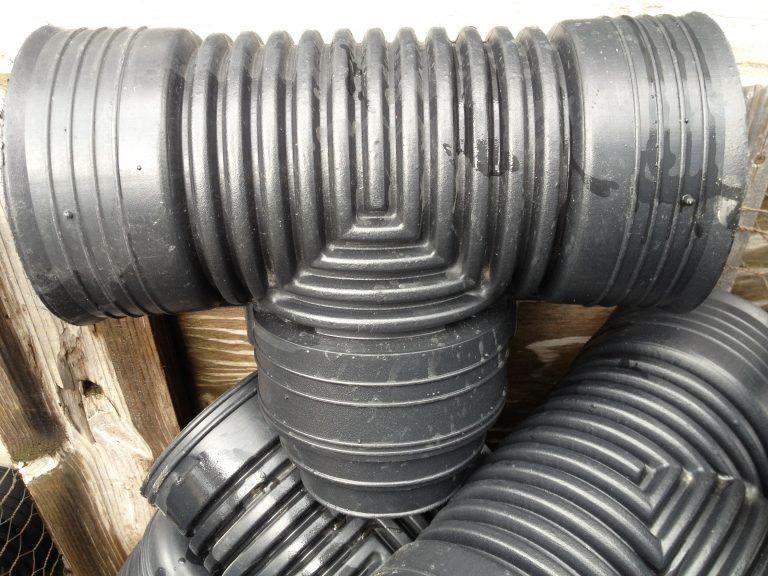 Black corrugated plastic pipes stacked in a three-way junction on a wooden pallet