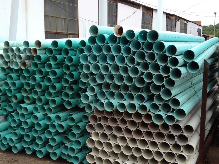 Stacks of teal and beige PVC pipes piled outside a building