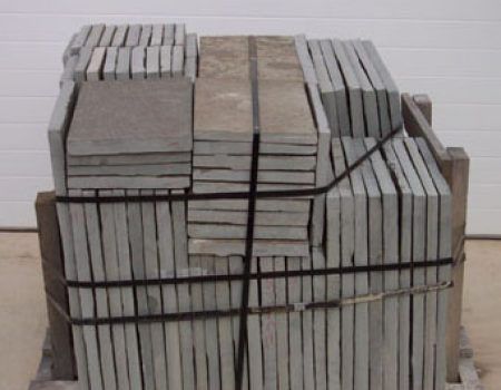 Stacked gray paving stones bundled with black straps on a pallet