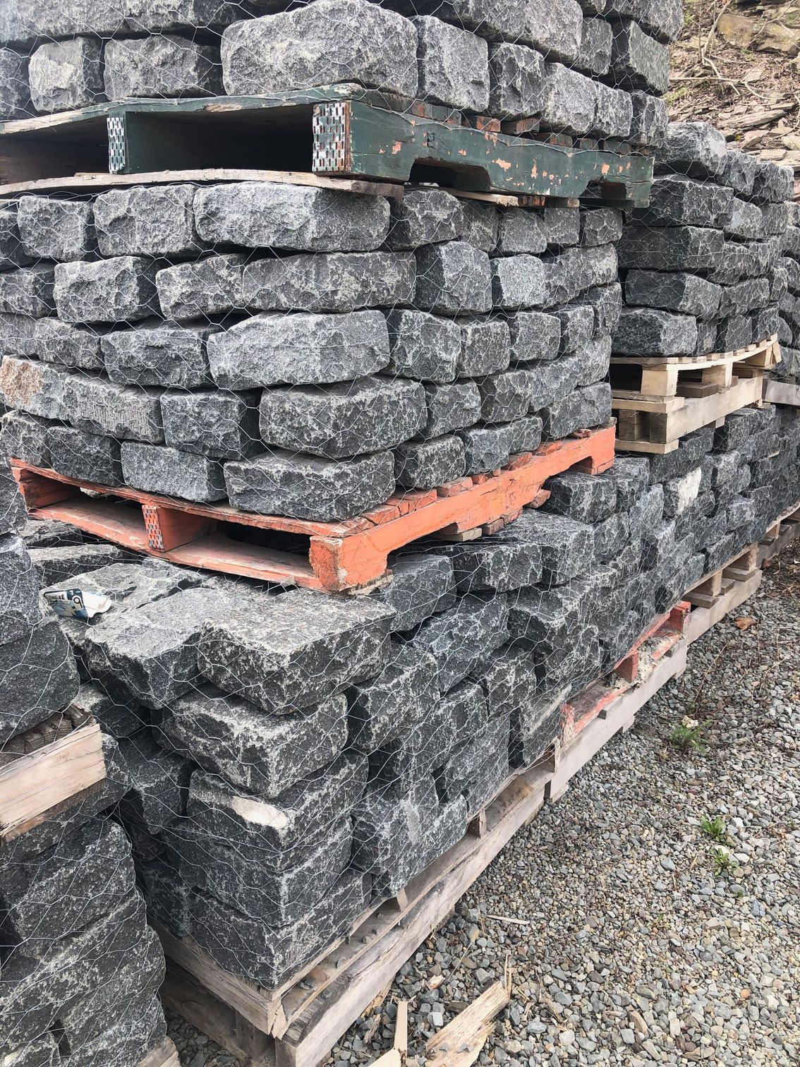 Stacks of gray paving stones on wooden pallets outdoors