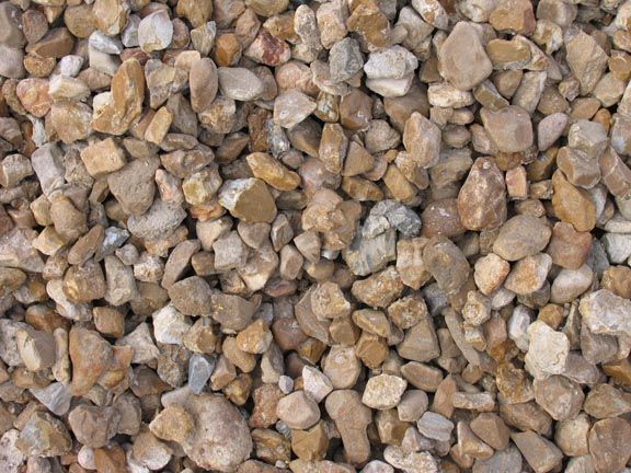 A close-up view of small, light brown and tan river stones and gravel texture.