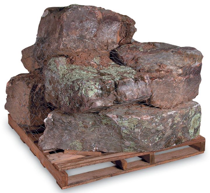 A wooden pallet piled with several large, rough-hewn, lichen-covered brown landscape stones.