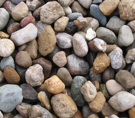 A top-down view of a dense collection of smooth, multi-colored river stones and pebbles of various shapes and sizes.
