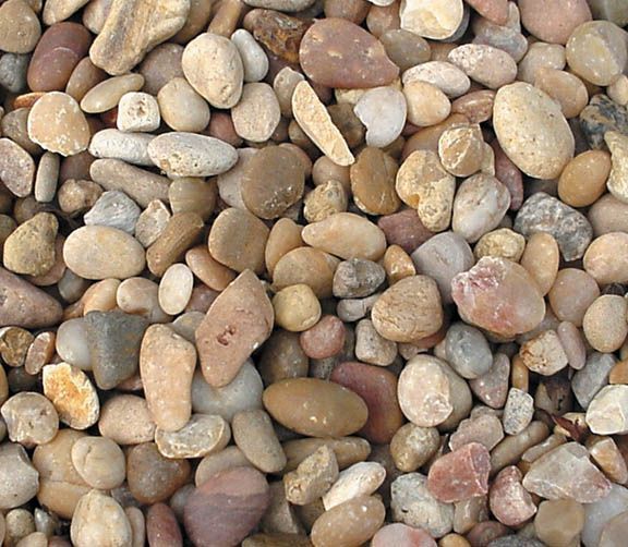 A close-up view of numerous smooth, rounded river stones in various shades of tan, brown, beige, and gray.