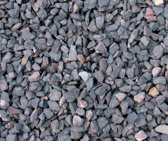 A close-up view of crushed gray stone gravel with varied textures and small reddish-brown inclusions.