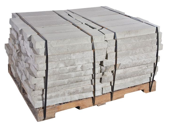 A wooden pallet loaded with stacked, rectangular light grey paving stones secured with two black plastic straps.