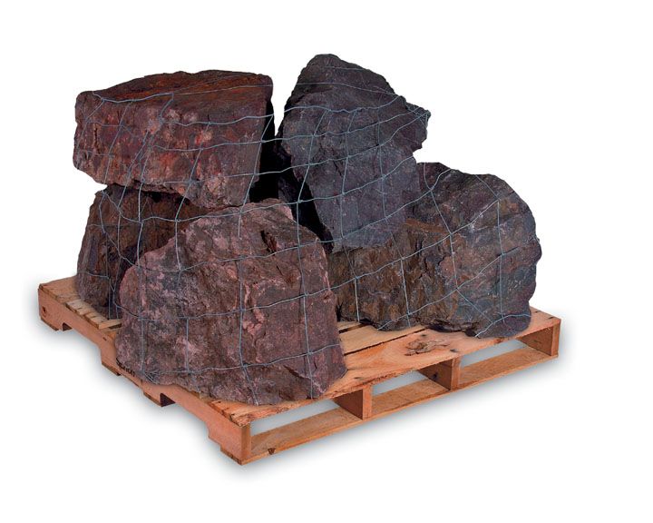 A wooden pallet loaded with large, dark-red landscaping rocks enclosed in protective wire mesh.