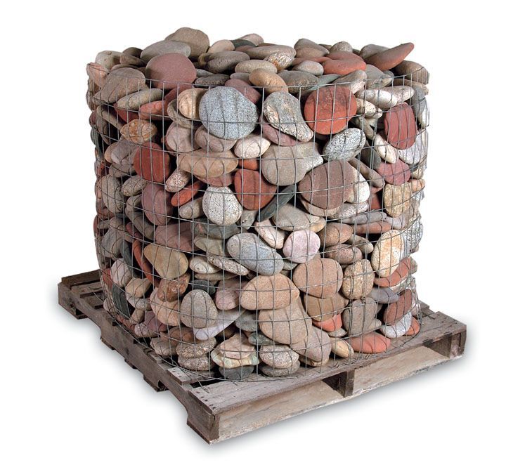 A wooden pallet holding a large, square wire basket filled with smooth, multicolored river rocks.