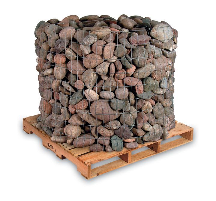 A pallet holding a wire crate filled with large, smooth, multicolored landscaping rocks.