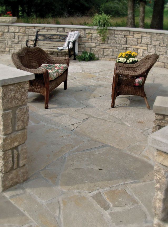 Wicker furniture arranged on a stone patio with a low rock wall in the background.
