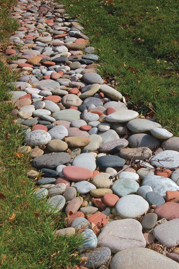 A path of smooth, multi-colored river stones curving through a grassy lawn.