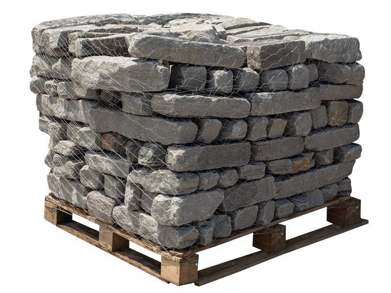 A pallet stacked with grey, rectangular natural stone blocks secured by netting against a white background.