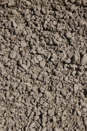 A close-up of light brown, jagged gravel or crushed stone.