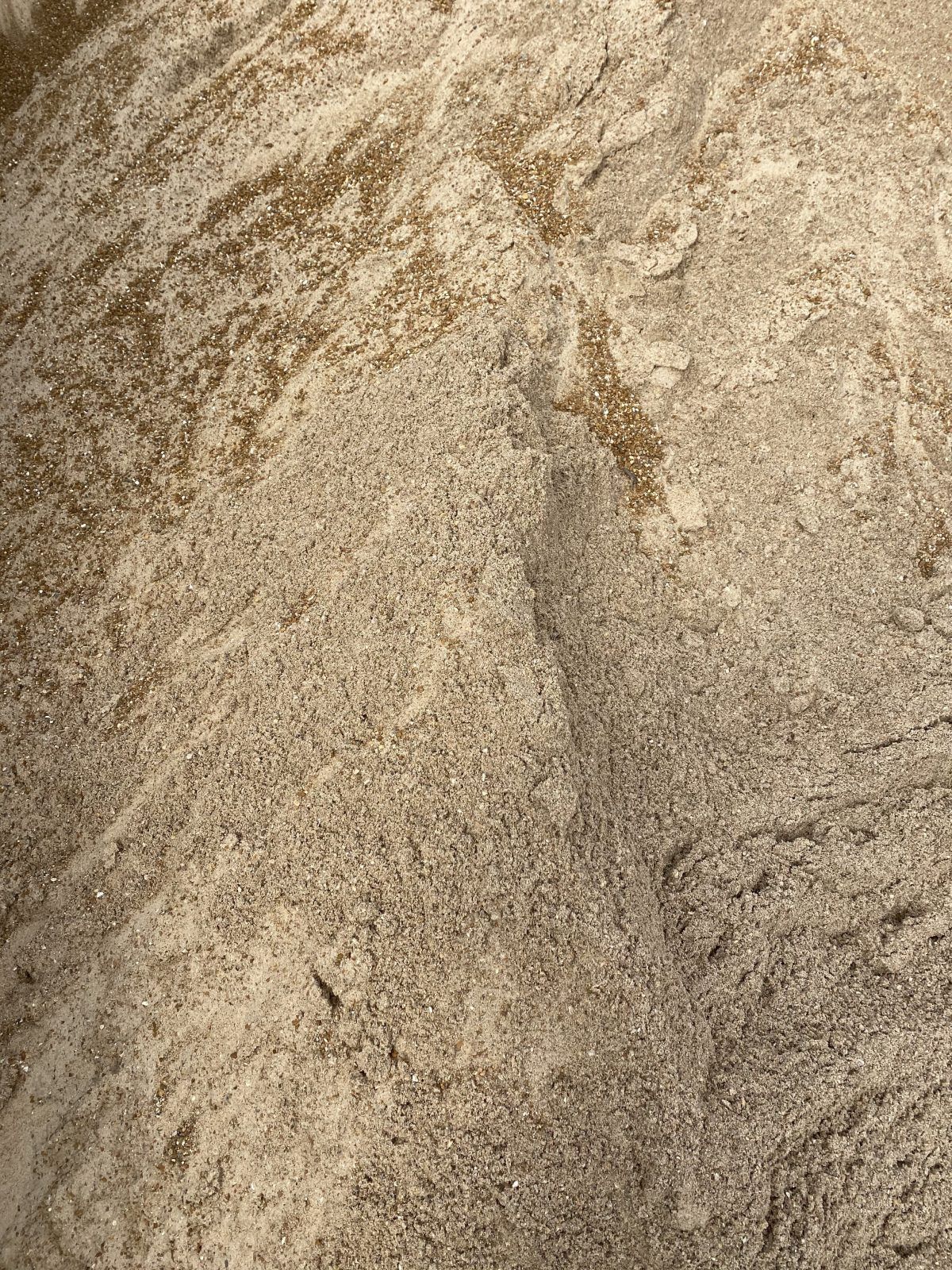 Close-up of beige sand with a central ridge and textured grain patterns