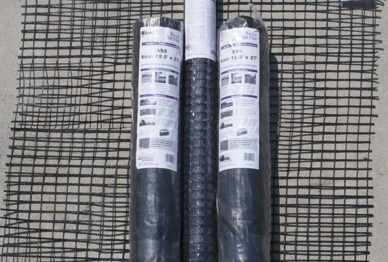 Two rolled black roofing membrane rolls with white labels on a wire mesh surface